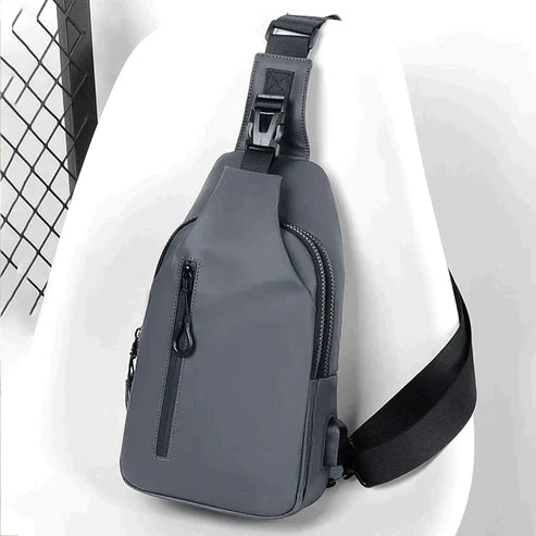 Sort unisex taske med justerbar rem, vandafvisende og med indbygget USB-oplader.