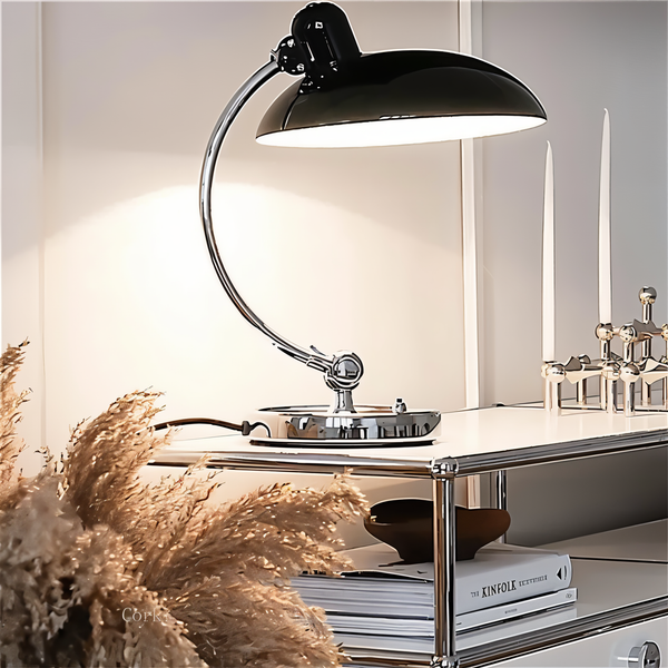 Justerbar bordlampe i jern med retrodesign og industriel stil, giver varmt lys til skrivebord eller læsehjørne.