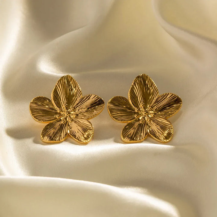 Nærbillede af dame vintage guldøreringe med detaljeret blomsterdesign. Festklare smykker.