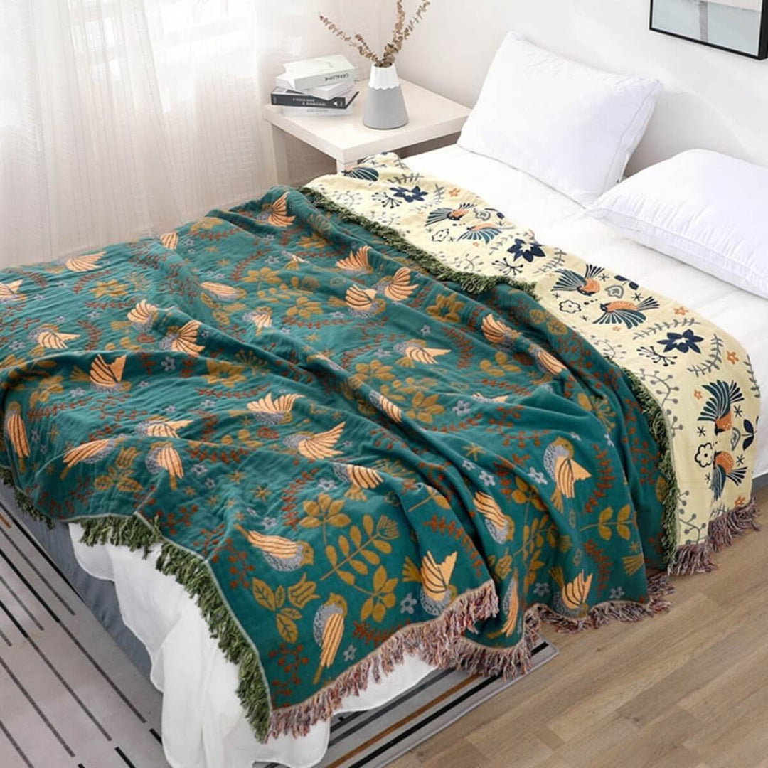 Vendbart skandinavisk plaids tæppe med fuglemønster, dobbeltsidet i blåt og hvidt, perfekt til sofa eller seng.