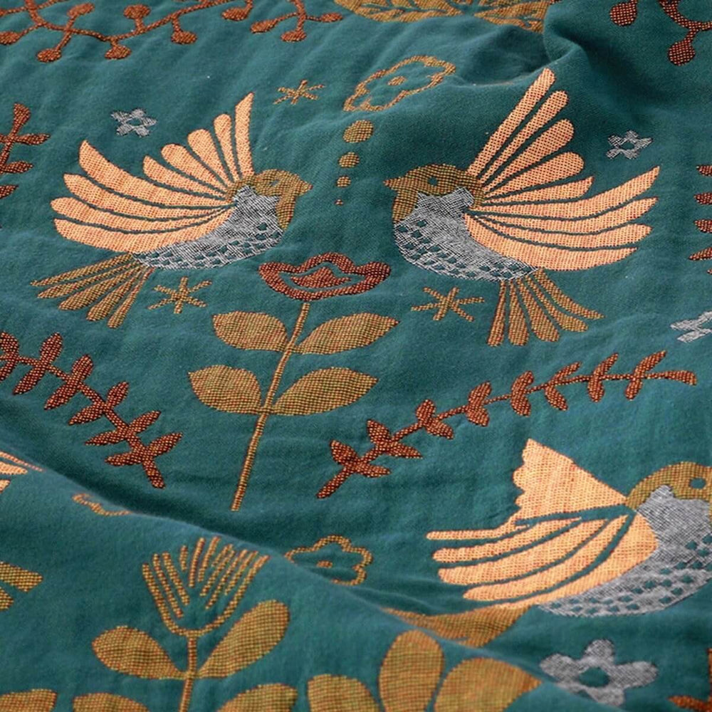 Vendbart skandinavisk plaids tæppe med fuglemønster, dobbeltsidet i blåt og hvidt, perfekt til sofa eller seng.