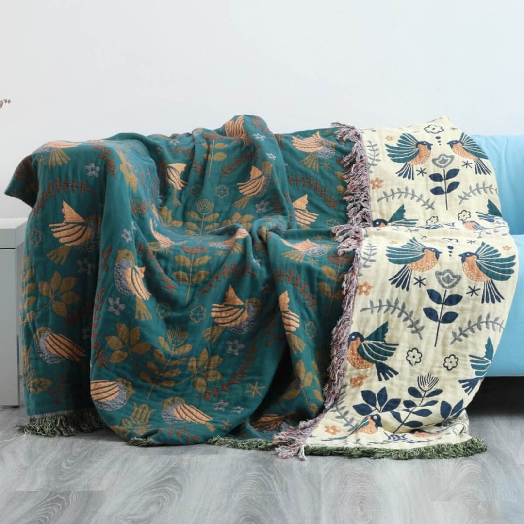 Vendbart skandinavisk plaids tæppe med fuglemønster, dobbeltsidet i blåt og hvidt, perfekt til sofa eller seng.