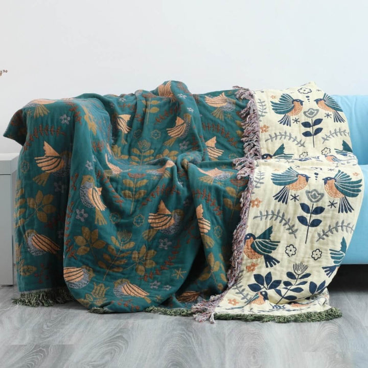 Vendbart skandinavisk plaids tæppe med fuglemønster, dobbeltsidet i blåt og hvidt, perfekt til sofa eller seng.