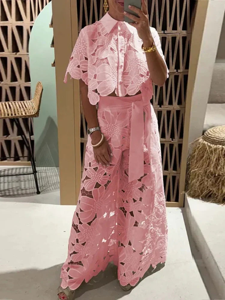 Let blondesæt til kvinder med blomsterdetaljer; elegant crop top og komfortable brede bukser.