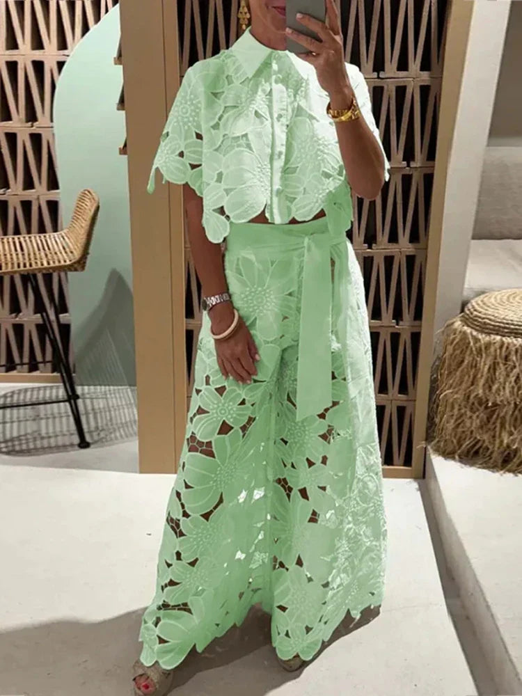 Nærbillede af det blomstrede blondestof på kvindens elegante crop top og de brede bukser.